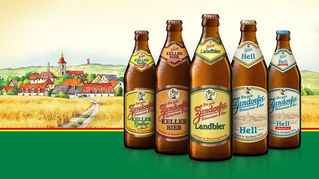 Fünf Bierflaschen der Marke Zirndorfer stehen vor einer gemalten ländlichen Landschaft.