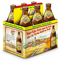 Sechserpack Bierflaschen in einer gelben Kartonverpackung mit Dorflandschaftsbild.