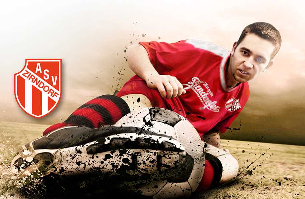 Ein Fußballspieler in einem roten Trikot grätscht nach einem Ball auf einem schlammigen Feld.